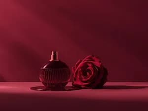 Парфюм с феромонами рядом с красной розой
