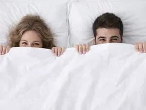 Мужчина и женщина выглядывают из-под белого одеяла